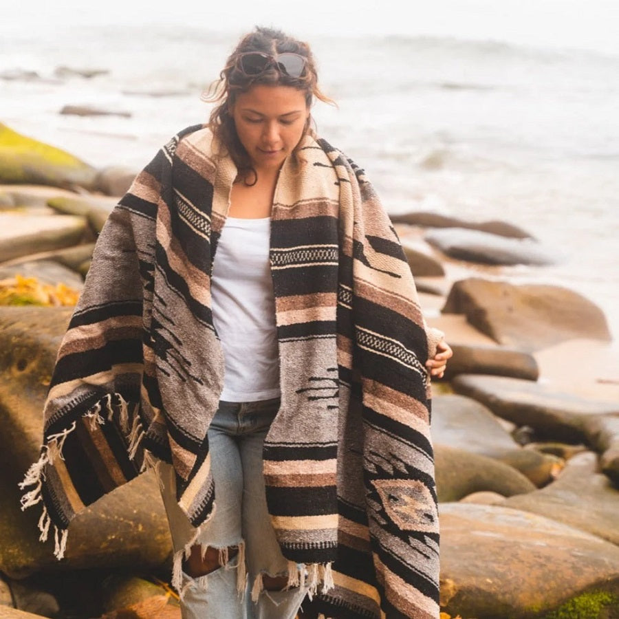 woman wearing blanket while exploring beach setting