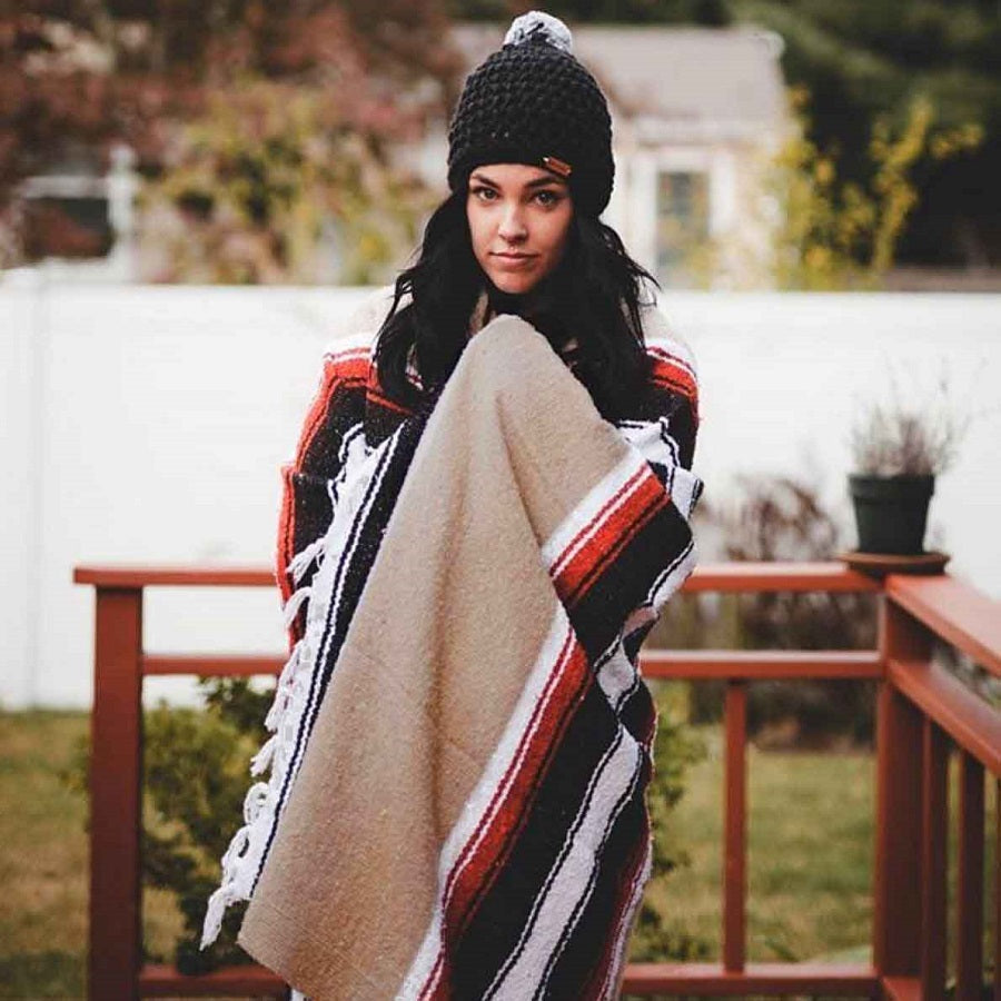 Woman wrapping up in beige coloured Mexican blanket