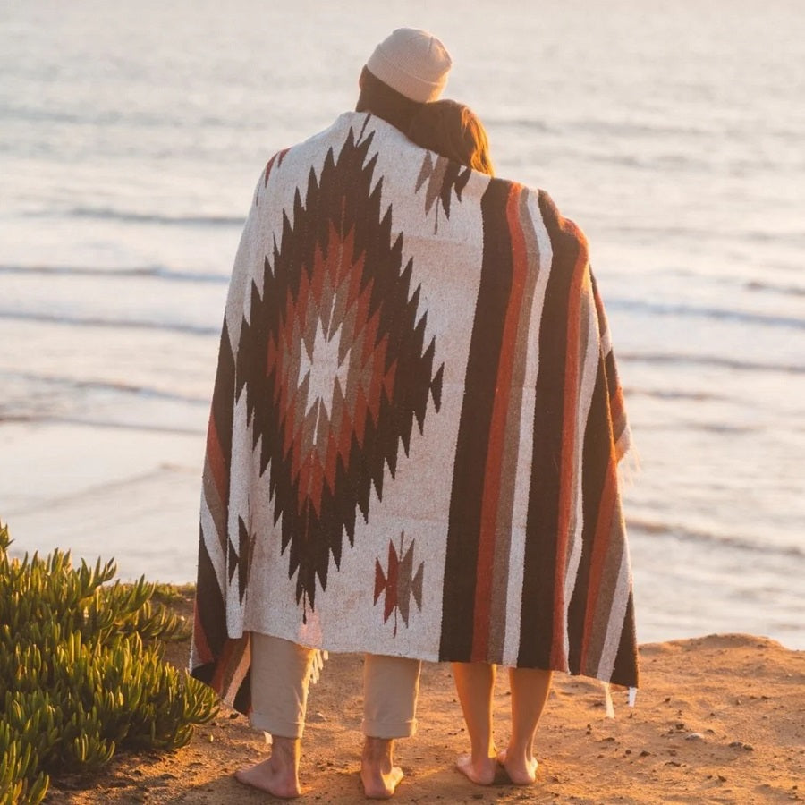 Couple wrapped up in blanket watching ocean