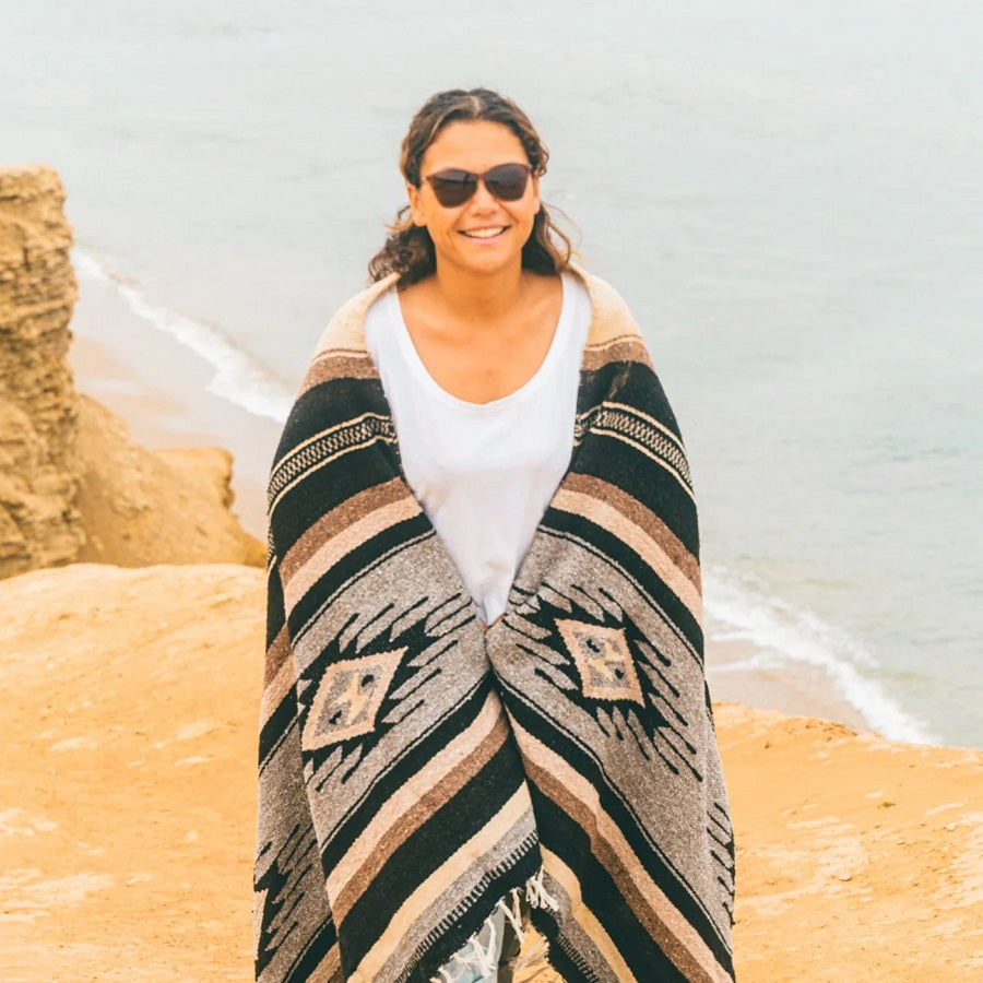 Woman wrapped in Mexican pattern blanket at the beach