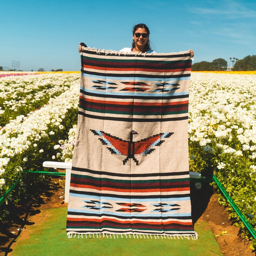 Large Mexican style blanket being held up in garden