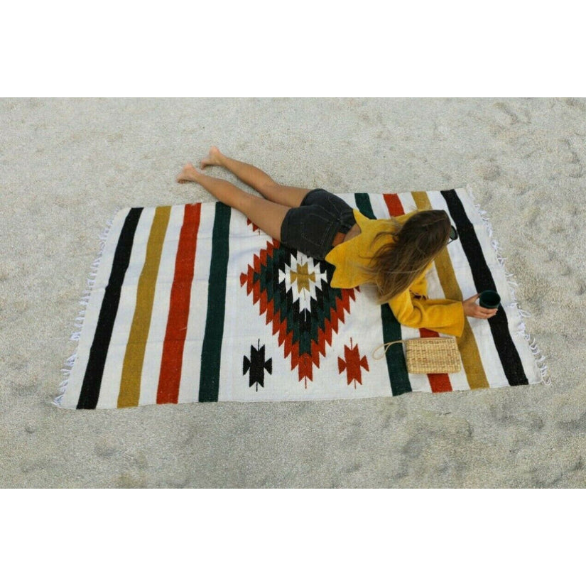 woman lying on white Saltillo Mexican blanket at the beach